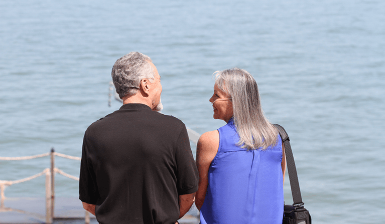 Woman on oxygen laughing with her husband at the lake.