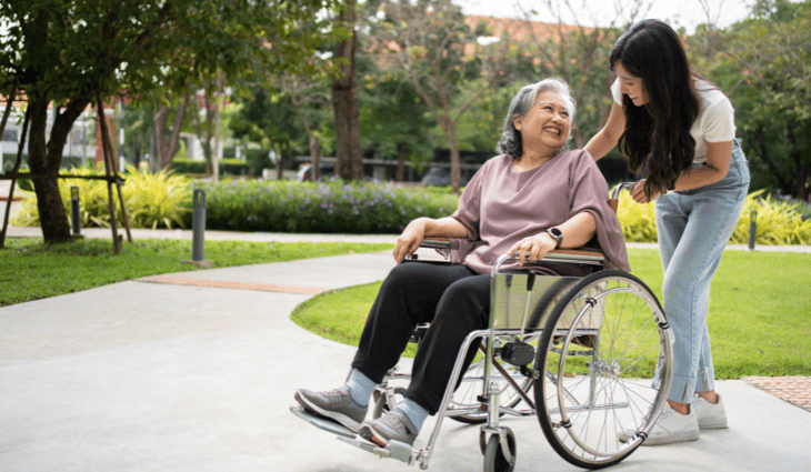 Happy older woman laughing and being pushed along by her daughter.