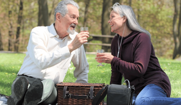 Woman on oxygen having a picnic in the park with her husband.