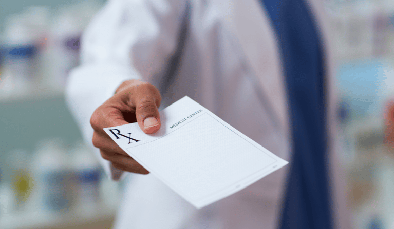 A Doctor handing over an unfilled out prescription.