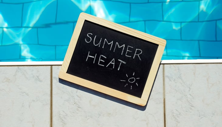 summer heat written on chalkboard by pool